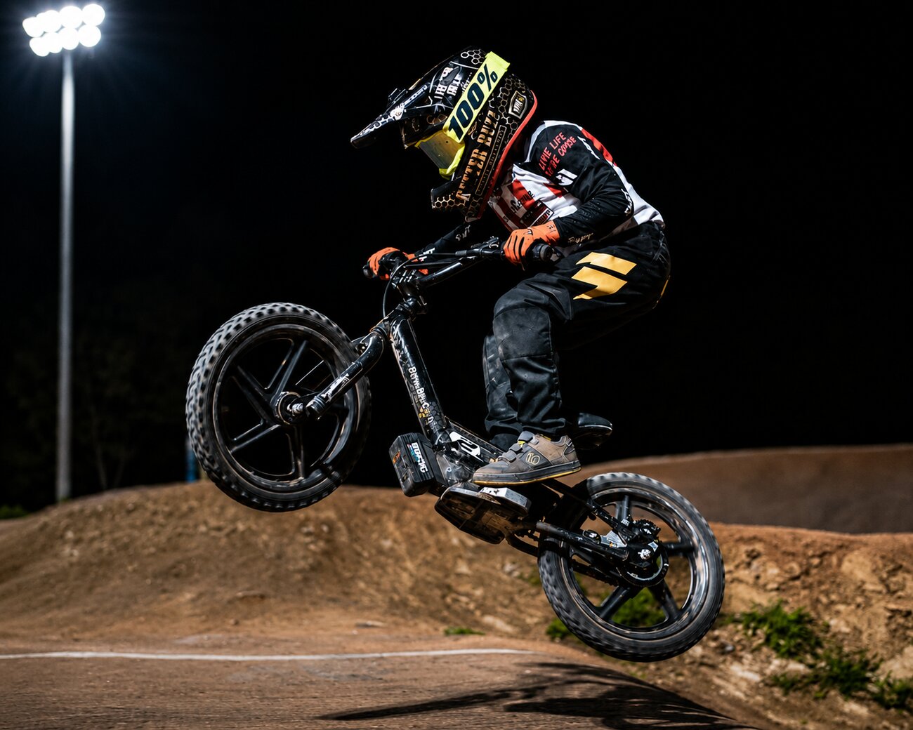 A BMX rider catching air off a jump under the lights at San Diego BMX